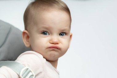 Bebek sandalyede otururken komik kızgın ve üzgün bir surat yapıyor.