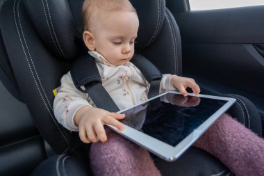 Bebek koltukta otururken tabletle oynuyor. Dijital teknolojiyle uğraşan bebek kavramı