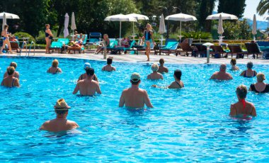 BUDVA, MONTENEGRO - EYLÜL 08, 2023: Açık havuzda bir otellerde su aerobiği yapan grup. Fitness kavramı ve suda eğlence