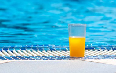 Bir bardak taze portakal suyu yüzme havuzunun yanında, yaz tatili konsepti..