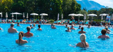 BUDVA, MONTENEGRO - EYLÜL 08, 2023: Açık havuzda bir otellerde su aerobiği yapan grup. Fitness kavramı ve suda eğlence