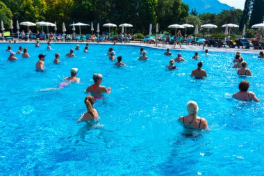 BUDVA, MONTENEGRO - EYLÜL 08, 2023: Açık havuzda bir otellerde su aerobiği yapan grup. Fitness kavramı ve suda eğlence