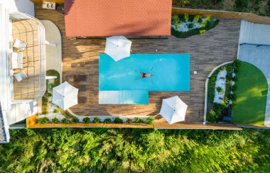 Lüks yüzme havuzunda yüzen bir adam. Havadan çekim. Dikkatsiz yaz tatili konsepti