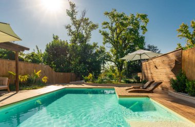 Şık bir villa havuzu, şezlonglar, palmiye ağaçları ve şemsiyeli, lüks ve rahatlatıcı bir atmosfer sağlıyor. Huzurlu lüks ve konfor kavramı özel bir inzivada veya tatil evinde