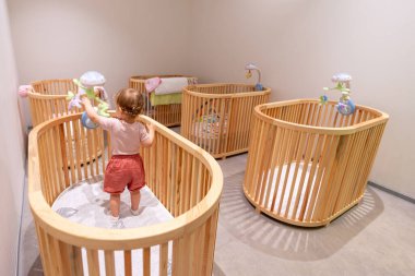 Çağdaş bir çocuk odasındaki ahşap karyolada duran ve oynayan neşeli bir çocuk. Çocuk yuvasında ya da anaokulunda eğlenceli etkileşim ve öğrenim kavramı