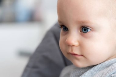 Çarpıcı mavi gözleri ve düşünceli bir ifadeyle sessiz bir merakı yakalayan bir bebeğin yakın çekimi. Kibar masumiyet kavramı ve huzurlu çocukluk anları