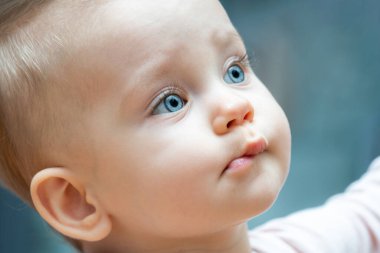 Parlak mavi gözlü ve meraklı bir ifadeyle yukarıyı nazikçe seyreden bir bebeğin yakın çekimi. Gençlik masumiyeti, keşif ve doğal güzellik kavramı.