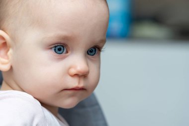 Gri elbiseli mavi gözlü bir bebeğin sakin ve huzurlu bir görüntüsü. Huzurlu bir görünüm sergiliyor. Nazik masumiyet kavramı ve genç sükuneti.