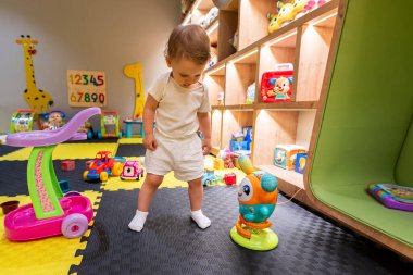 Young child exploring a cheerful playroom filled with fun toys and activities. Concept of indoor play and early childhood development