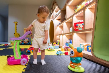 Canlı ve modern bir oyun odasında oyuncaklarla oynayan bir bebek. Çocuk yaratıcılığı, eğlence ve içeride öğrenme kavramı