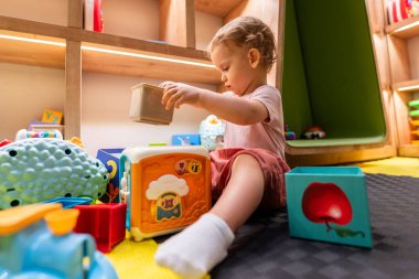 Çocuklar için renkli oyun odasında eğitim bloklarıyla oynayan çocuk.