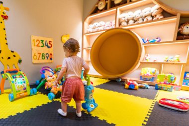 Eğlenceli ve eğitici bir oyun odasında oyuncak süpürgeyle temizlik yapıyormuş gibi yapan meraklı çocuk.