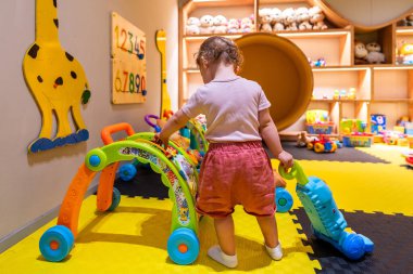 Parlak bir oyun alanında etkileşimli oyuncaklar ve eğitim oyunlarıyla meşgul olan çocuk