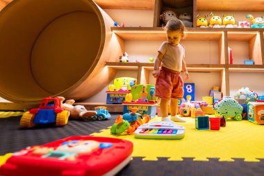 Bebekler, eğlence, öğrenme ve yaratıcı keşifler için tasarlanmış kapalı bir oyun odasında renkli oyuncaklarla çevrili.