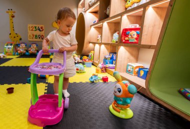 Canlı ve modern bir oyun odasında oyuncaklarla meşgul olmanın tadını çıkaran bir çocuk. İç mekan eğlencesi, yaratıcılık ve öğrenme kavramı