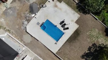Tamamlanmamış bir havuzun havuz manzarası. Mavi koruyucu kaplamalı ve inşaat alanını çevreleyen.