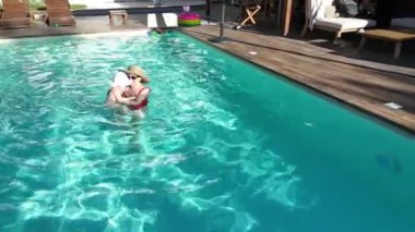 Sevgi dolu anne ve bebek, açık havada yüzme havuzunun keyfini çıkarıyorlar.