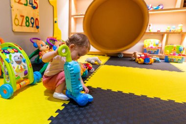 Erken öğrenim için renkli ve güvenli bir oyun odasında oyuncak süpürgeyle temizlik becerilerini keşfeden küçük bir çocuk.