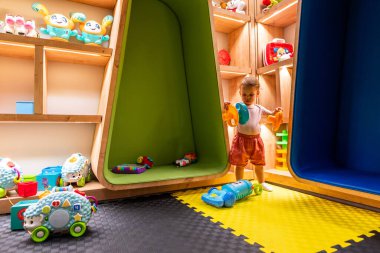 Oyuncak ve oyunları eğlence ve öğrenim için canlı ve etkileşimli bir oyun odasında keşfeden çocuk