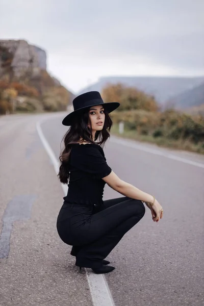ファッションアウトドア美しい女性の写真暗い髪のエレガントな衣装で山の中で道路上にポーズ — ストック写真