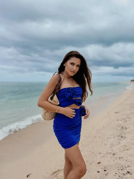 ビーチでポーズをとるエレガントな青のドレス姿の黒髪の美しいセクシーな女性のファッション屋外写真 — ストック写真