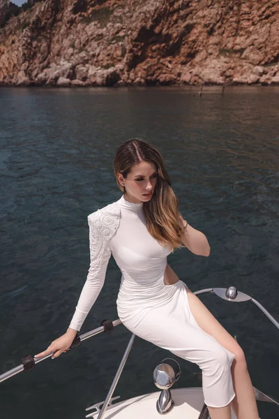 在游艇甲板上轻松自在地坐着 在静海中航行的漂亮女人 深色头发 身穿华丽的白衣 — 图库照片