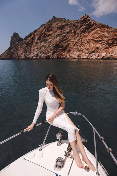 ヨットのデッキでリラックスした豪華な白いドレスで暗い髪の美しい女性のファッション 地中海でセーリング — ストック写真