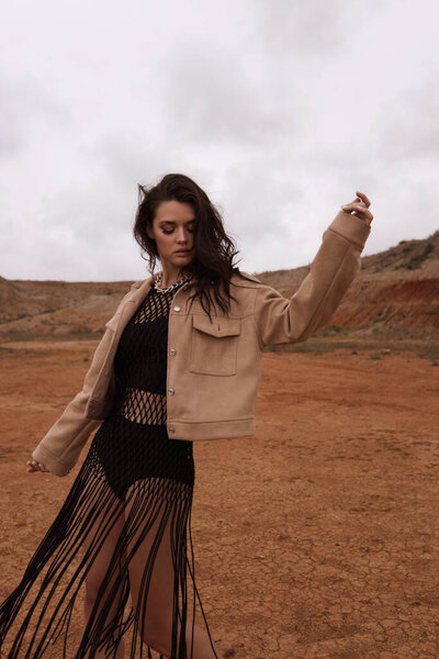 fashion outdoor photo of beautiful woman with dark hair in casual clothes posing in desert of Cyprus