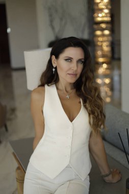 Şık elbiseli, siyah saçlı, şık bir otelde poz veren güzel bir kadının moda fotoğrafı.
