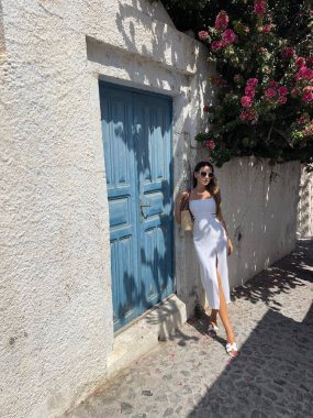 Güzel, siyah saçlı, zarif elbiseli ve Santorini adasında gezen güzel bir kadının moda fotoğrafı.