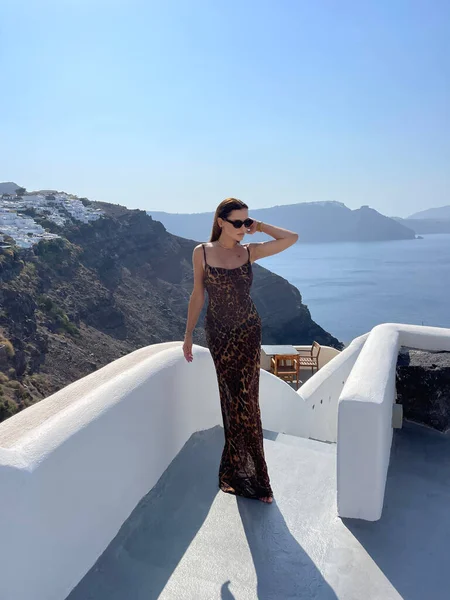 Güzel, siyah saçlı, zarif elbiseli ve Santorini adasında gezen güzel bir kadının moda fotoğrafı.