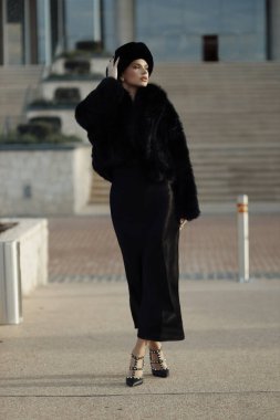 Siyah kürklü, şapkalı, dışarıda poz veren güzel Slav bir kadının moda fotoğrafı.