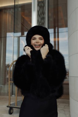 Siyah kürklü, şapkalı, dışarıda poz veren güzel Slav bir kadının moda fotoğrafı.