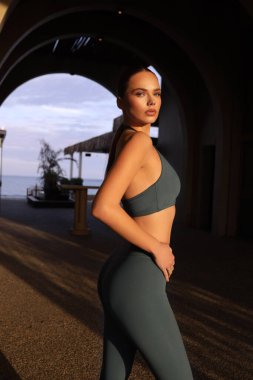 Kemerde poz veren zarif spor takım elbiseli, siyah saçlı güzel Slav bir kadının moda fotoğrafı.