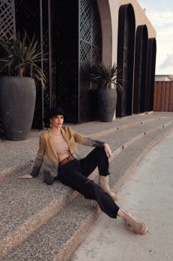 Havalı kıyafetler içinde siyah şapkalı, güzel Slav bir kadının Limasol caddesinde poz verirken çekilmiş moda fotoğrafı.