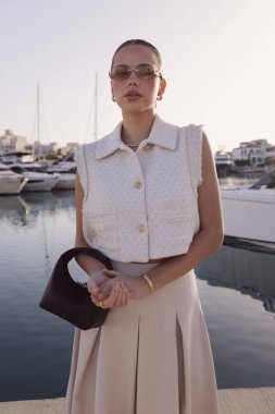Kıbrıs 'ta yatlarla marinada poz veren zarif klasik elbiseli, koyu renk saçlı güzel bir kadının moda fotoğrafları.