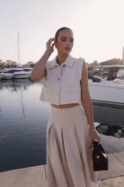 Kıbrıs 'ta yatlarla marinada poz veren zarif klasik elbiseli, koyu renk saçlı güzel bir kadının moda fotoğrafları.