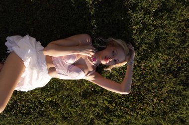 Güzel, şehvetli, sarışın, zarif elbiseli, aksesuarlı ve bahçeli güzel bir villada poz veren güzel bir kadının moda fotoğrafı. 