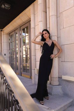 Güzel, siyah saçlı, şık siyah elbiseli ve güzel villada poz veren aksesuarlı güzel bir kadının moda fotoğrafı.