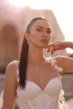 Güzel, açık hava fotoğrafında siyah saçlı, lüks elbiseli, aksesuarlı güzel bir villada klasik tarzda poz veren güzel bir kadın.