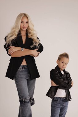 Güzel bir ailenin moda fotoğrafı, sarı saçlı, şık giyinmiş, yakışıklı oğluyla stüdyoda poz veren güzel bir anne.