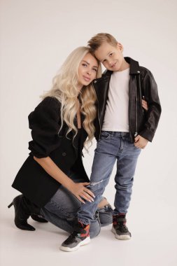 Güzel bir ailenin moda fotoğrafı, sarı saçlı, şık giyinmiş, yakışıklı oğluyla stüdyoda poz veren güzel bir anne.