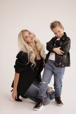 Güzel bir ailenin moda fotoğrafı, sarı saçlı, şık giyinmiş, yakışıklı oğluyla stüdyoda poz veren güzel bir anne.