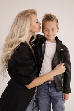 Güzel bir ailenin moda fotoğrafı, sarı saçlı, şık giyinmiş, yakışıklı oğluyla stüdyoda poz veren güzel bir anne.