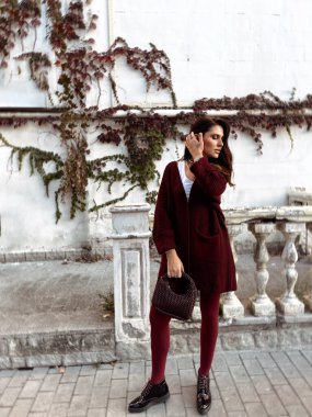 Şık bordo elbiseli, siyah saçlı, sokaklarda dolaşan güzel bir kadının moda fotoğrafı.
