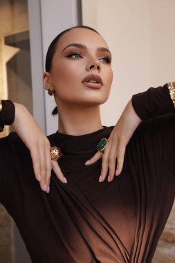 Şık bordo elbiseli ve zarif iç mekanlarda poz veren siyah saçlı güzel bir kadının moda fotoğrafı.