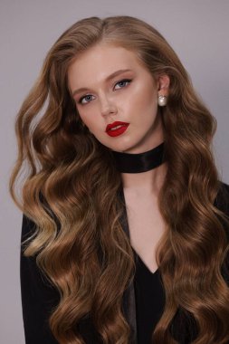 Stüdyoda poz veren siyah kıvırcık saçlı güzel bir kadının moda fotoğrafı.