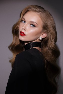 Stüdyoda poz veren siyah kıvırcık saçlı güzel bir kadının moda fotoğrafı.