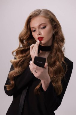 Stüdyoda poz veren siyah kıvırcık saçlı güzel bir kadının moda fotoğrafı.