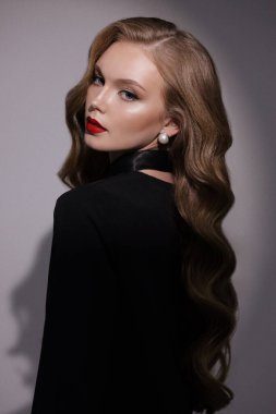 Stüdyoda poz veren siyah kıvırcık saçlı güzel bir kadının moda fotoğrafı.